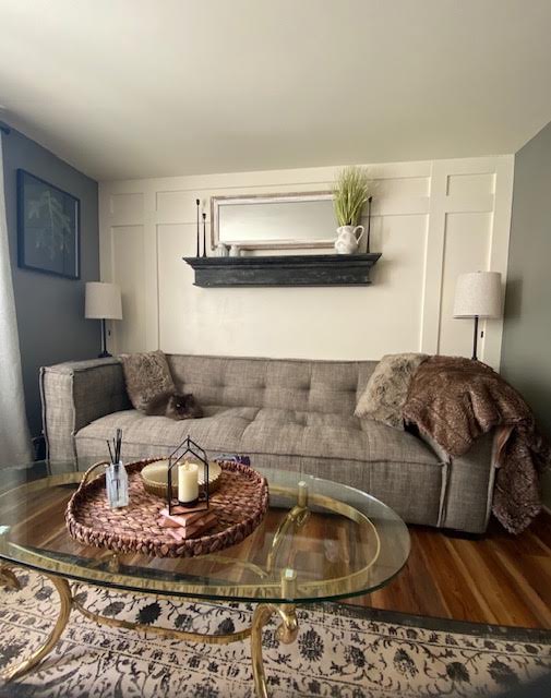 Living room with a grey sofa, white board and batten, and a black mantel shelf