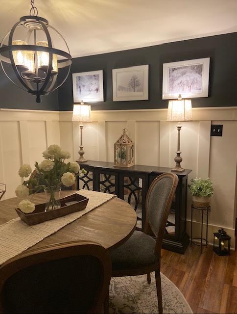 Dining room with a dark painted wall, white board and batten paneling, and a black orb chandelier
