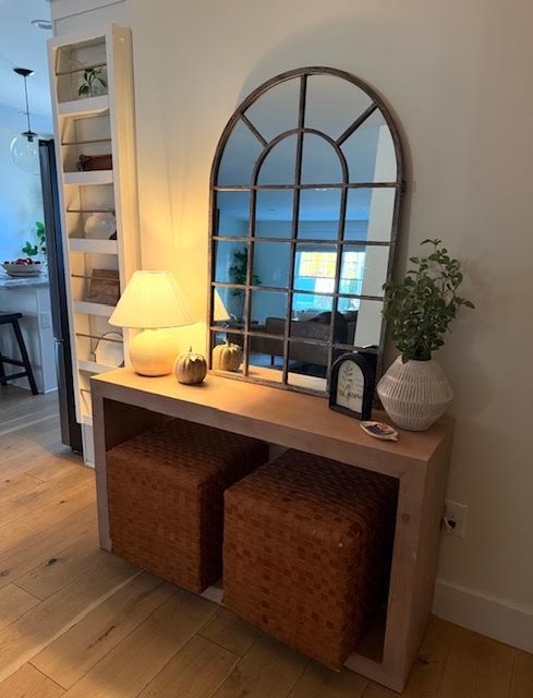 Entry console with arched window mirror and woven ottomans