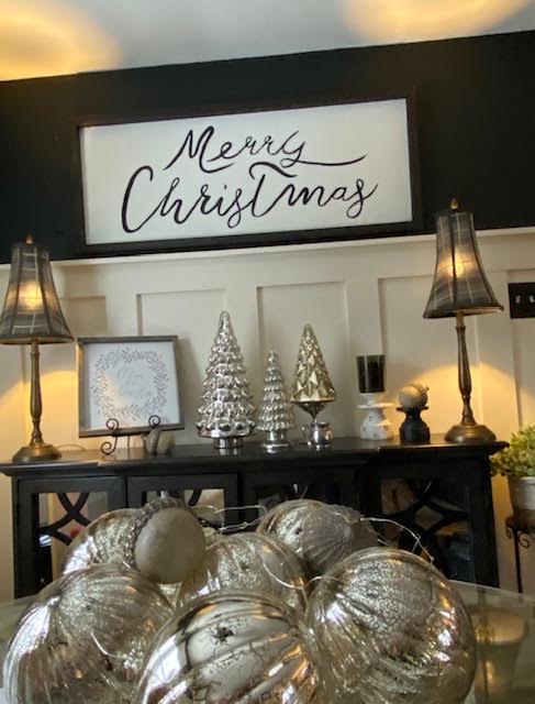 Black console styled for the holidays with mercury glass trees, plaid lampshades, and a Merry Christmas sign