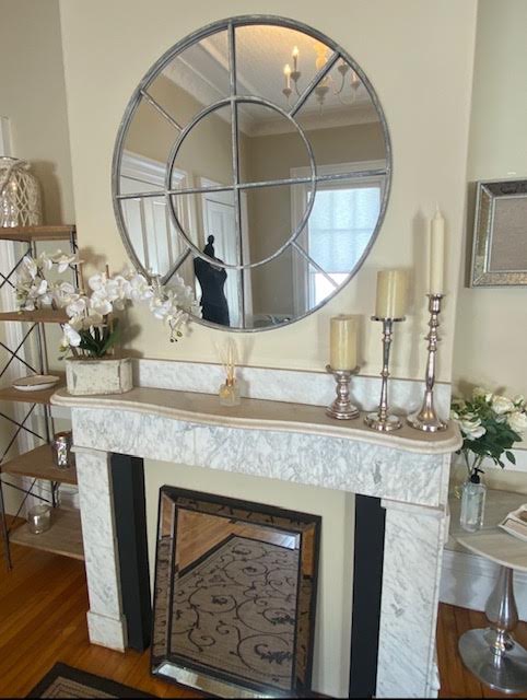 Marble mantel styled with white orchids, pillar candles, and tall silver candlesticks